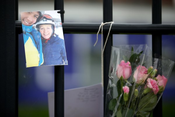 A photograph and flowers hang on the fence outside Corpus Christi Catholic College in tribute to Ann Maguire (Getty Images) 