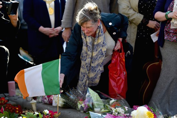 A mourner places an Irish flag among the flowers in Glasgow. Photo: PA