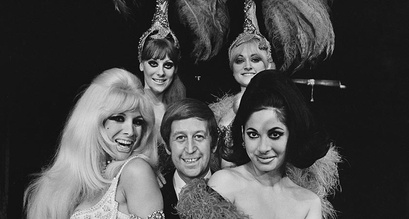 English publisher, club owner, and property developer Paul Raymond (1925 - 2008) with his Raymond Revuebar dancers Carole Ryva, Jean Crabtree, Lady Flan, and Sandra Bunting, 21st July 1967. The dancers will be visiting Aden, Yemen, to entertain British Army troops stationed there for the Aden Emergency. (Photo by C. Maher/Express/Hulton Archive/Getty Images)