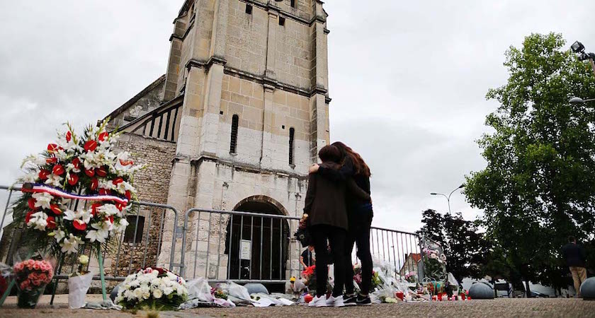 People stand in front of a make shift memorial in front of the Saint-Etienne du Rouvray church on July 27, 2016, after the priest Jacques Hamel was killed on July 26 in his church during a hostage-taking claimed by Islamic State group. France probes an attack on a church in which two men described by the Islamic State group as its "soldiers" slit the throat of a priest. An elderly priest had his throat slit in a church in northern France on July 26 after two men stormed the building and took hostages. The attack in the Normandy town of Saint-Etienne-du-Rouvray came as France was still coming to terms with the Bastille Day killings in Nice claimed by the Islamic State group. / AFP / CHARLY TRIBALLEAU (Photo credit should read CHARLY TRIBALLEAU/AFP/Getty Images)