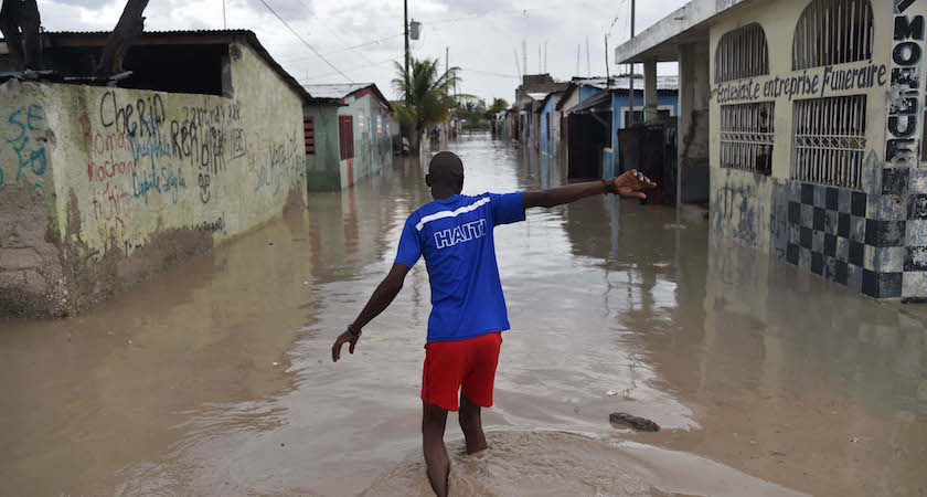 TOPSHOT - A man walks down a flooded street, in a neighbourhood of the commune of Cite Soleil, in the Haitian Capital Port-au-Prince, on October 4, 2016. Hurricane Matthew slammed into Haiti, triggering floods and forcing thousands to flee the path of a storm that has already claimed three lives in the poorest country in the Americas. / AFP / HECTOR RETAMAL (Photo credit should read HECTOR RETAMAL/AFP/Getty Images)